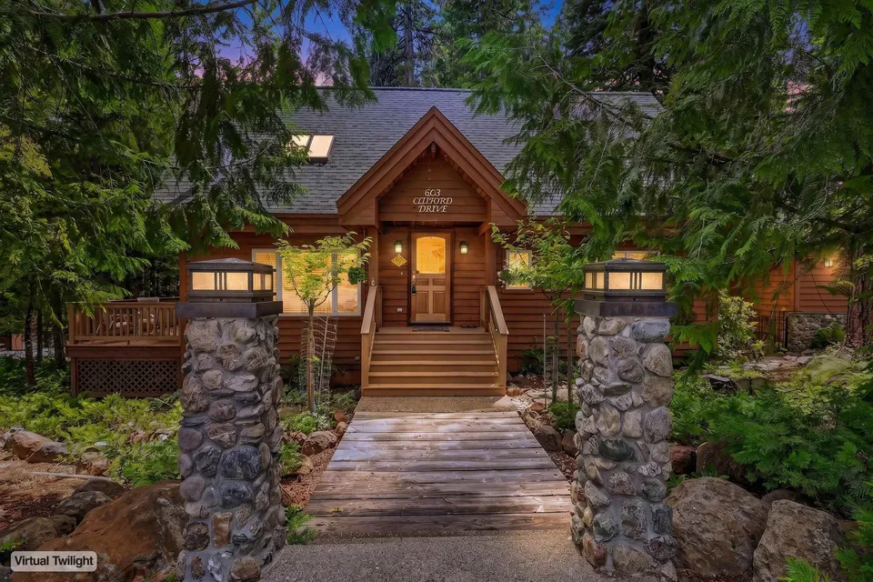 603 Clifford Drive, a wood cabin glowing at twilight among the trees